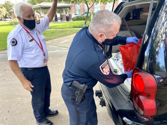 Kissimmee Police Chief Jeff O'Dell puts a bag of food in the back of a vehicle. NEWS-GAZETTE PHOTO/BRIAN MCBRIDE