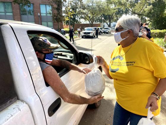 Newly Kissimmee Mayor Olga Gonzalez hands a turkey to a local resident. NEWS-GAZETTE PHOTO/BRIAN MCBRIDE