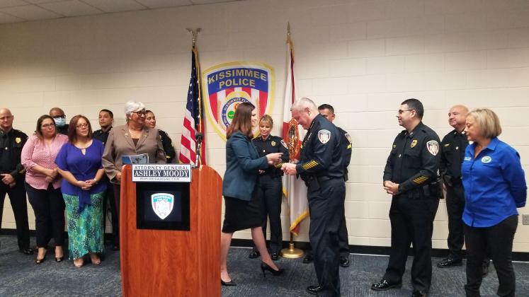 Florida Attorney General Ashley Moody makes a presentation to Kissimmee Police Department Chief Jeff O'Dell Wednesday as part of her Thin Line Tribute program. PHOTO/KEN JACKSON