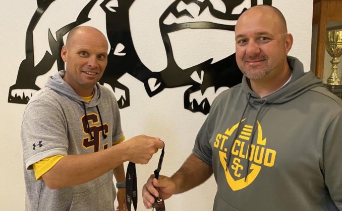 Bryan Smart (left), with nothing to do with a coaching whistle now as the Bulldogs' athletic director, passes the football reigns onto Mike Short. PHOTO/ST. CLOUD H.S.