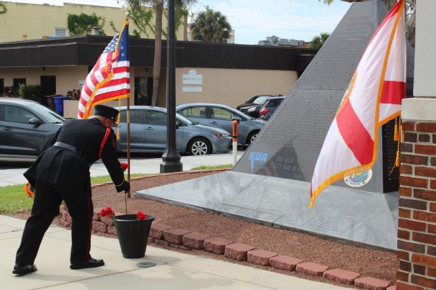 A member of the Kissimmee Fire Department Honor Guard places a red rose at the base of the city's monument honoring its retired at passed at a memorial service Friday. PHOTO/KEN JACKSON