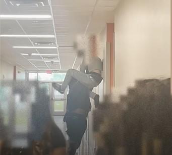 This still from video footage shows an adult identified as Christopher Ferguson holding a Tohopekaliga High student against the wall near the ceiling on Monday. PHOTO/OSCEOLA COUNTY SHERIFF'S OFFICE