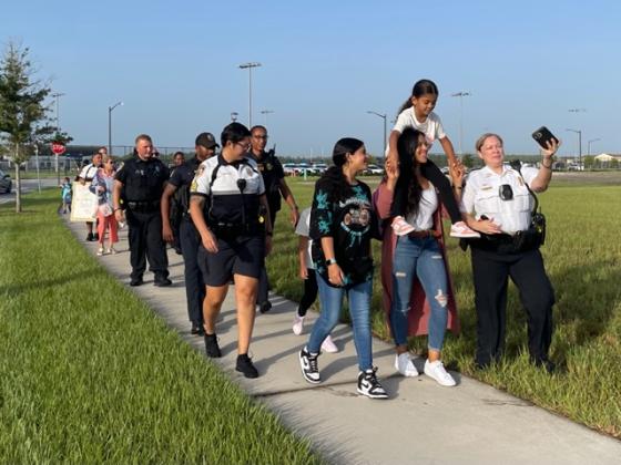 New kindergartner Zarah Baxter gets a ride on mom Sadia's shoulders on the walk from Heroes Park to Laureate Park Elementary School. PHOTO/LINDSEY TELLEZ
