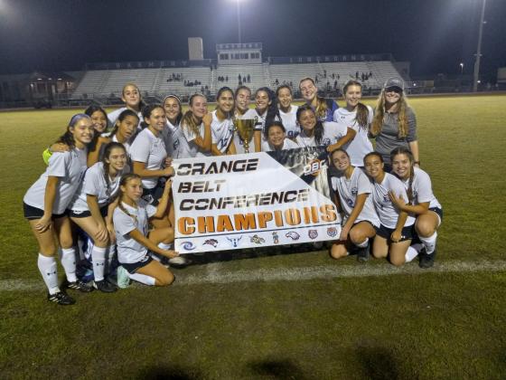 : Storm players pose with championship trophy and banner after breaking a 12-game winless streak against Harmony to claim their first OBC championship. PHOTO/J. DANIEL PEARSON