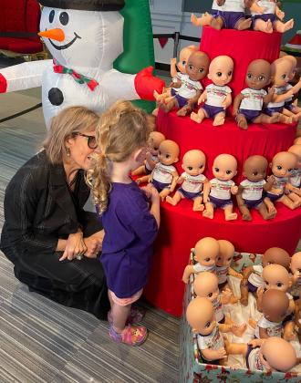 Give Kids The World President &amp; CEO Pamela Landwirth helps a wish child choose a Baby Alive doll Thursday at Give Kids the World Village. PHOTO/CHRIS MILLER