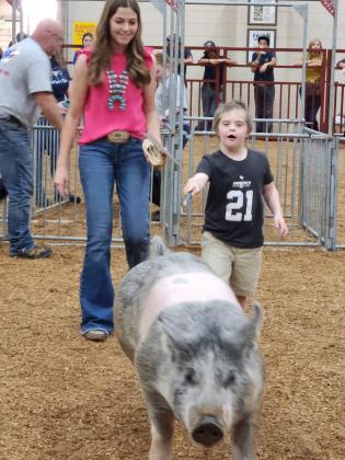 PHOTO/KEN JACKSON Eight-year-old Ian is high on the hog — at least this one, Barbie — as he shows off Barbie at Saturday’s special needs livestock show, under the watchful eye of KVLS exhibitor Bailee Jeannin, 16.