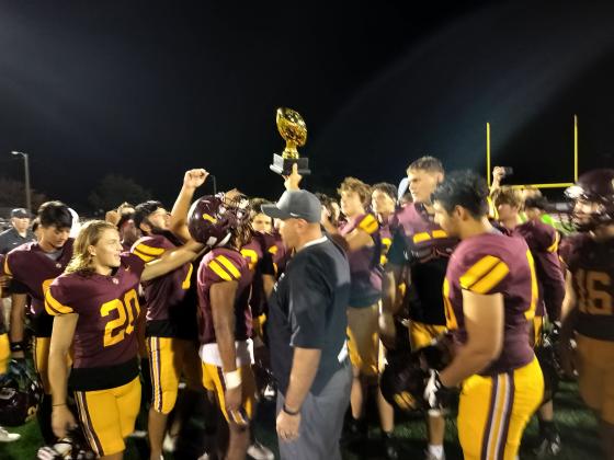 Coach Mike Short holds the Prescriptions Unlimited Bowl Trophy aloft as his team celebrates its 45-6 win over Lake Region on Wednesday night. (Photo by J. Daniel Pearson)