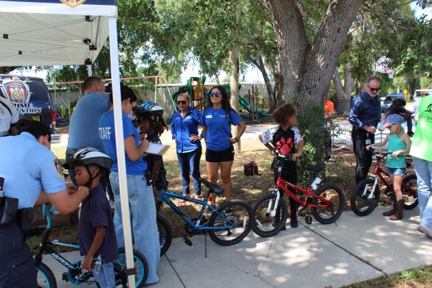 Safety first: Kissimmee Police Department officers fit the new bike recipients with new bike helmets.PHOTO/KEN JACKSON