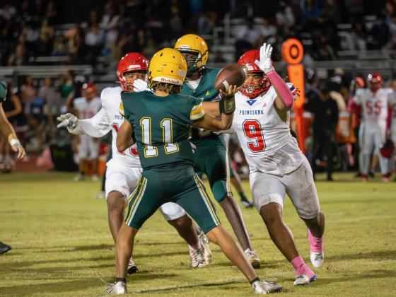 Liberty quarterback Richard Monplasir is under fire from Poinciana defensive end Jamel George in Friday's game. PHOTO/MARIO CASAMALHUAPA
