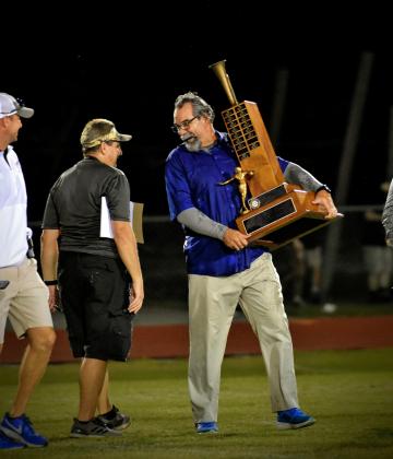 Don Simon, holding the Brass Bugle Trophy after Harmony’s win over St. Cloud in 2022, is returning to the Longhorns’ sideline after a two-year absence from coaching.