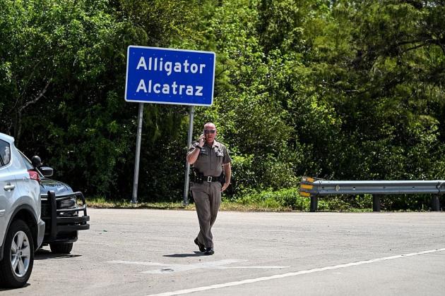 A Florida Highway Patrol officer looks on as protesters gather to demand the closure of the immigrant detention center known as "Alligator Alcatraz" at the Dade-Collier Training and Transition Airport in Ochopee, Florida, on July 22, 2025.  (Photo by CHANDAN KHANNA/AFP via Getty Images)