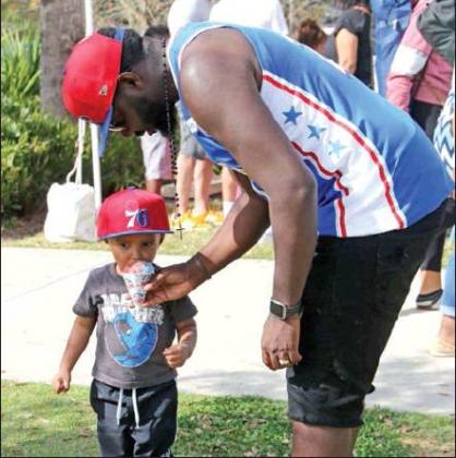 News-Gazette Photo/NaNcy BriGham Jaiden, 3, of St. Cloud, is treated to a sno-cone with the help of his father, Marcus.