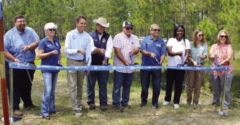 Members of the Partin family, Osceola County commissioners Ricky Booth and Cheryl Grieb, St. Cloud Mayor Nathan Blackwell, and SFWMD leadership cut the ribbon on the $2 million flood control project. PHOTO/TERRY LLOYD