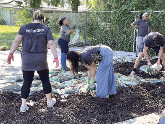 Volunteers prepped and placed rubber mulch in the play area of the Boys and Girls Club Friday. PHOTO/DEBBIE DANIEL