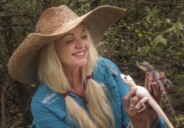 Gatorland’s Savannah Boan holds the park’s new editions, a rare leucistic gator (left) with little to no pigment, and a traditional baby gator. PHOTO/GATORLAND