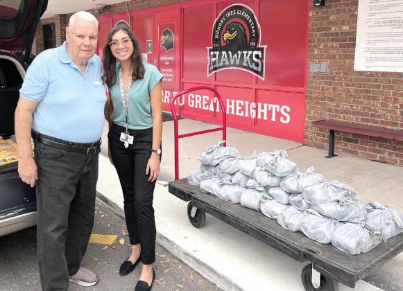 Guidance counselor Kristal Albino receives CarePacks from St. Cloud Cares volunteer Russell Banks at Hickory Tree Elementary School. PHOTO/DEBBIE DANIEL
