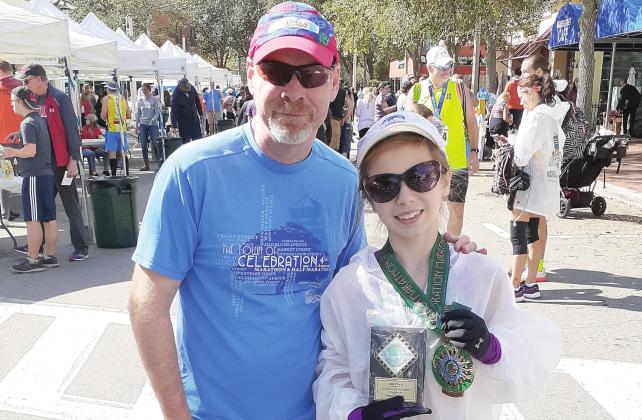 Briar-Rose Honewill, 14, stands with a plaque and medal for her second-place finish in the Celebration Marathon women 19 and under category in January of 2020. At left is race director Ken Zambito. SUBMITTED PHOTO
