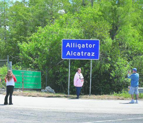 People take pictures in front of the Alligator Alcatraz sign at the entrance to the Dade-Collier Training and Transition Airport. (Photo/Getty Images via News Service of Florida)