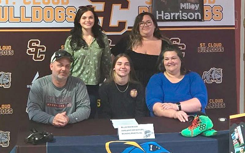 Surrounded by family, Miley Harrison (center) signs her letter-of-intent to wrestle at Lakeland College in Wisconsin. (Photo/Mike Short)