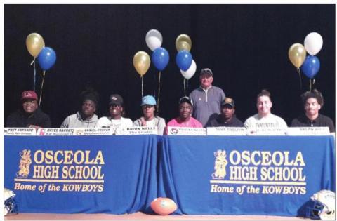 Osceola Head Coach Doug Nichols (back row) is with his eight seniors who signed scholarship offers on National Letter of Intent Day in 2020. .