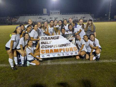 : Storm players pose with championship trophy and banner after breaking a 12-game winless streak against Harmony to claim their first OBC championship. PHOTO/J. DANIEL PEARSON