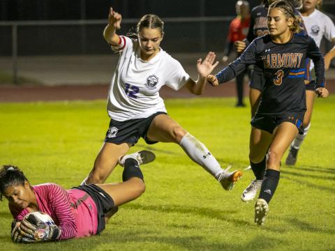 Harmony goaltender Karla Marrero makes a huge second half stop of Anna Balba’s (12) point blank shot as Longhorns’ defender Ava Duval (3) looks on in Friday’s Orange Belt Conference girls soccer championship, a 3-2 Harmony win. PHOTO/MARIO CASMALHUAPA
