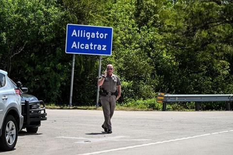 A Florida Highway Patrol officer looks on as protesters gather to demand the closure of the immigrant detention center known as "Alligator Alcatraz" at the Dade-Collier Training and Transition Airport in Ochopee, Florida, on July 22, 2025.  (Photo by CHANDAN KHANNA/AFP via Getty Images)
