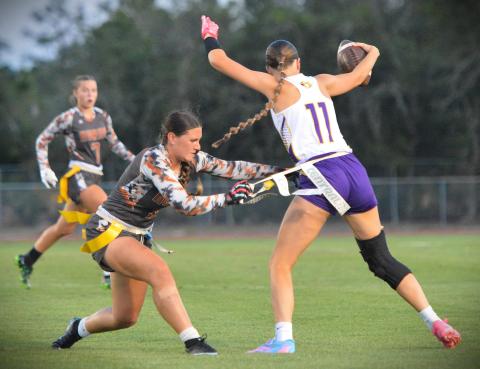 Harmony's Khloe Cook-Osani pulls the flag of Fort Pierce Central's Braelyn Hartnett in Thursday's regional final, a 15-7 Harmony win. (Photo/Katie Williams)