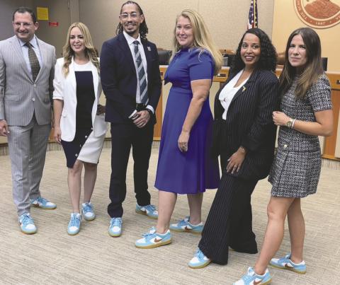 Osceola School Board members Bethzaida Garcia, Anthony Cook, Paula Bronson, Terry Castillo and Heather Kahoun and Superintendent Dr. Mark Shanoff (at left) model their new symbolic matching sneakers. PHOTO/DEBBIE DANIEL