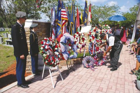 A member of the American Legion Riders places a wreath at the St. Cloud Memorial Day observance as cadets from the St. Cloud High School Army Junior ROTC stand tall. (Photo/Terry Lloyd)