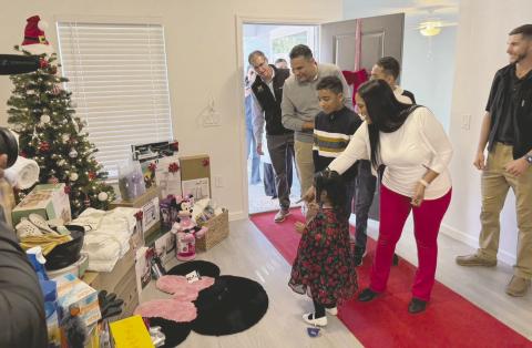 Gloria and Francisco, with their three children, enter their new home at a ceremony on Friday. PHOTO/DAVID CHIVERS
