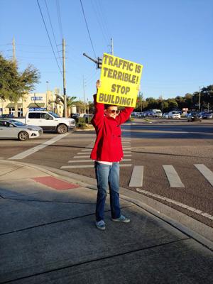 Monique Costantino, who created the Osceola Traffic Facebook page, holds a sign at the intersection of Old Canoe Creek and Neptune roads. Photo/Osceola Traffic Facebook page