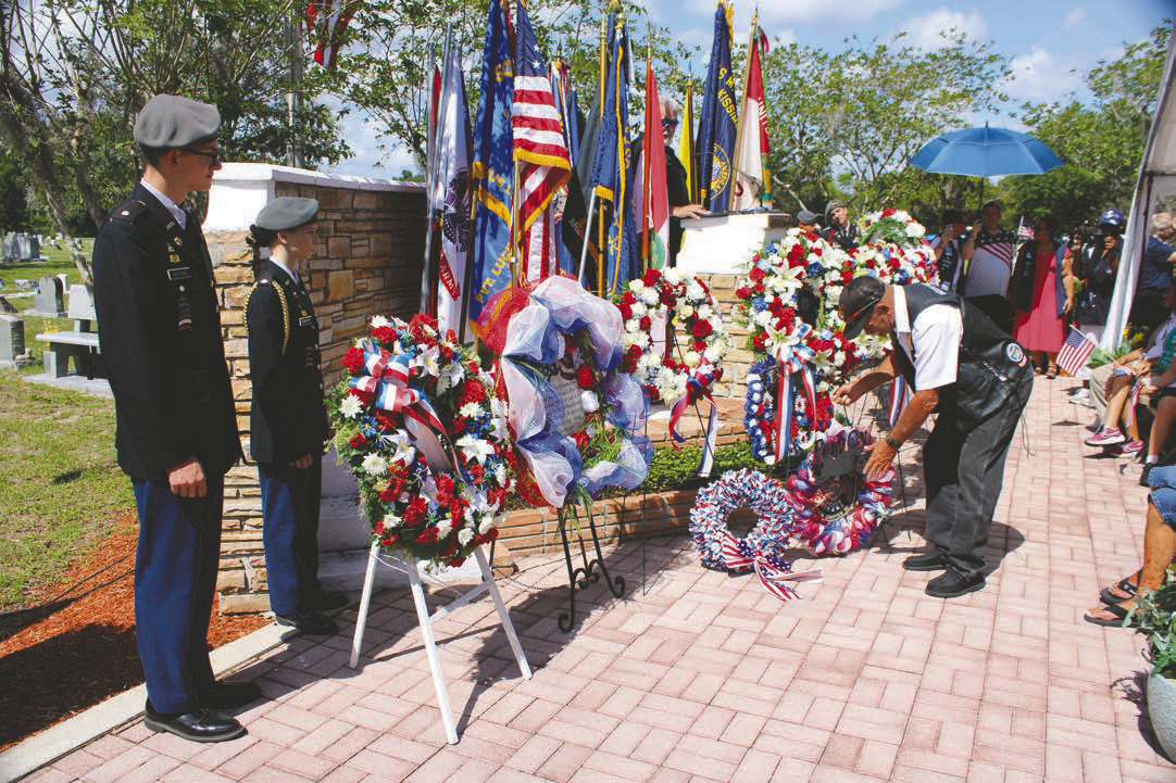 A member of the American Legion Riders places a wreath at the St. Cloud Memorial Day observance as cadets from the St. Cloud High School Army Junior ROTC stand tall. (Photo/Terry Lloyd)