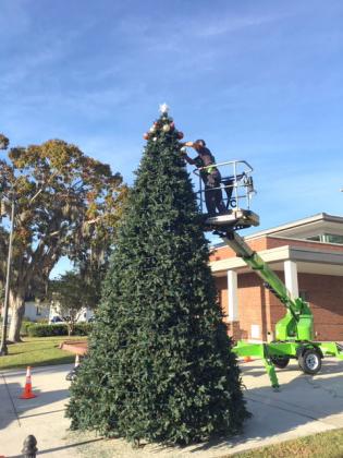 A city of Kissimmee staffer begins to decorate the Christmas tree in front of City Hall on Monday. The tree lighting ceremony will be Tuesday, Dec. 3, at 5 p.m. The event will feature holiday music, treats and the special visit of Santa Claus.