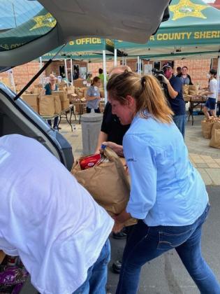 A volunteer loads a bag of food into the back of a vehicle.