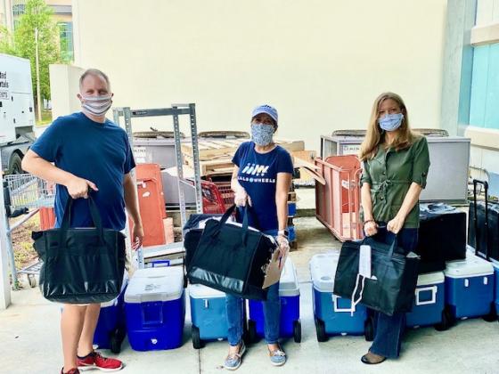 From left, chef Chris May,  Wilda Belisle, senior vice president of nutrition at the Osceola Council on Aging and Courtney Daniels, owner of Kent Custom Homes, prepare to go on a Meals on Wheels run at the council.