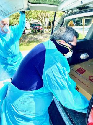 Kissimmee Mayor Jose Alvarez puts food in the back of a vehicle. NEWS-GAZETTE PHOTO/BRIAN MCBRIDE