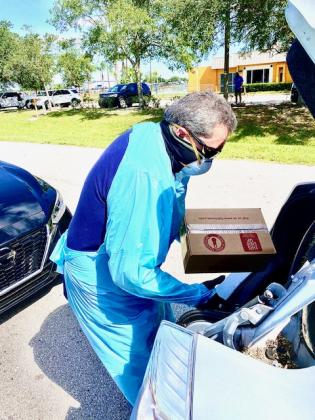 Kissimmee Mayor Jose Alvarez places food in the truck of a car.
