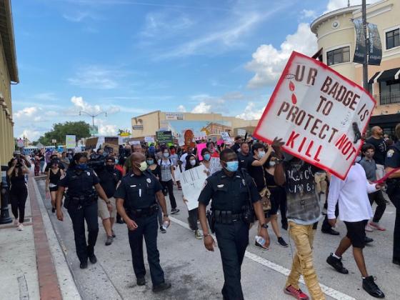 Community members and law enforcement officers march together in downtown Kissimmee to stand against police brutality. NEWS-GAZETTE PHOTO/BRIAN MCBRIDE