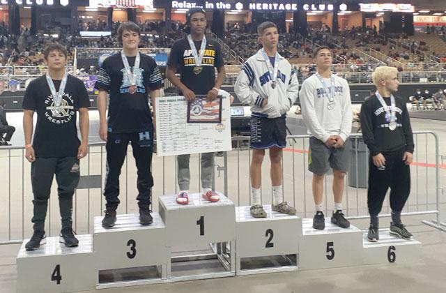 Jaekus Hinds, top step, accepts his first place medal after winning the Class 3A State Championship at 138 pounds. Hines put on a dominating performance in beating South Dade’s Alex Cotto, 18-5, in the final.  Photo by J. Daniel Pearson.