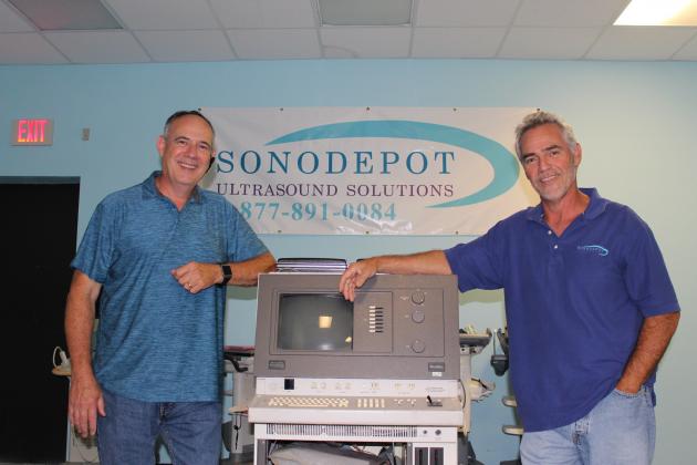 Jack (left) and Floyd McAuliffe pose with one of the first ultrasound machines the family business services, a mid-1980s model.