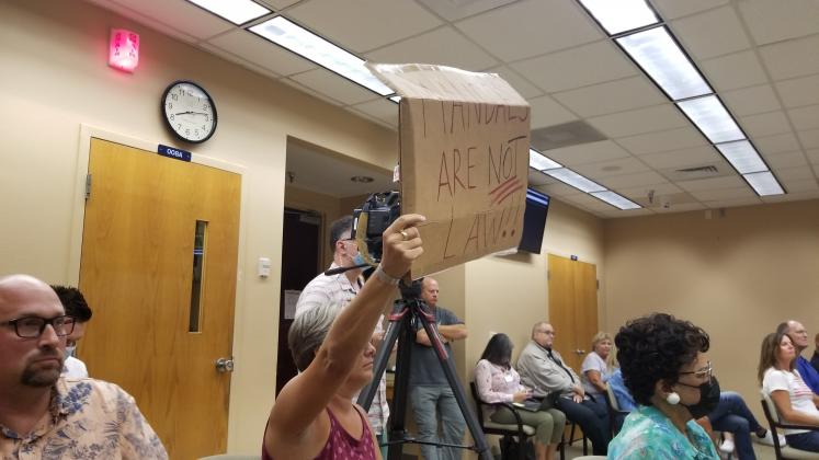 A School Board meeting attendee Monday holds a sign against a mask mandate. PHOTO/KEN JACKSON 