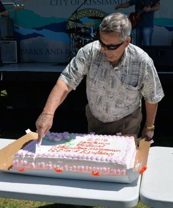 Kissimmee Mayor Jim Swan, in the comfortable clothes many got to see him in, cutting the cake at the 2015 Kowtown Festival. PHOTO/CITY OF KISSIMMEE