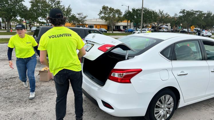 Volunteers load up families's cars during Tuesday's Food Share/AESG/City of Kissimmee distribution. PHOTO/CHRIS MILLER