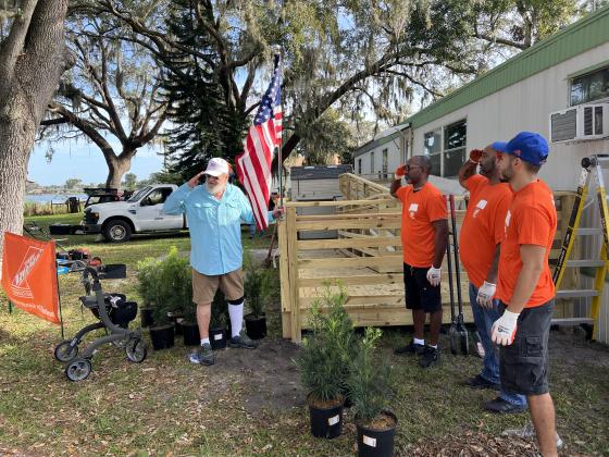 PHOTO/OSCEOLA COUNCIL ON AGING Members of the Home Depot “Helping Homebound Heroes” program salute the U.S. flag and retired Army field lineman/E-4 James Mead of Kissimmee. The crew made some improvements to his home Nov. 30.