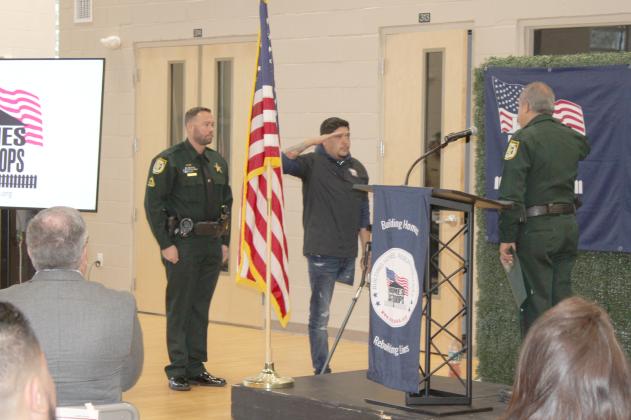 Sgt. 'Lito" Dilone acknowledges receipt of a military-style challenge coin from Osceola County Sheriff Marcos Lopez at Saturday's Homes for Our Troops kickoff. He appeared with President George W. Bush at Walter Reed Army Medical Center. PHOTO/TERRY LLOYD