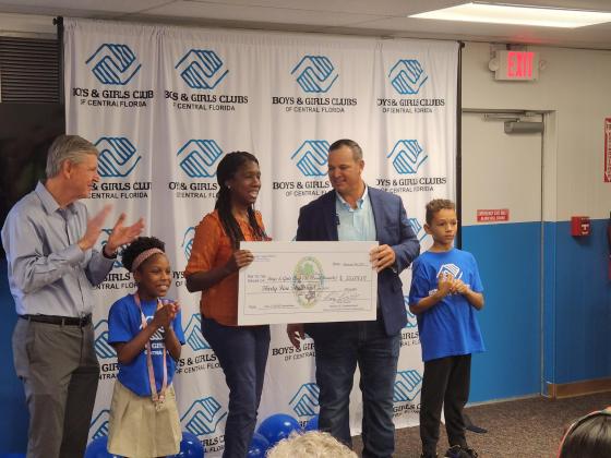 County Commissioner Ricky Booth presents Boys & Girls Club of Central Florida Senior Development Officer $35,000 to donate to the club. PHOTO/KEN JACKSON