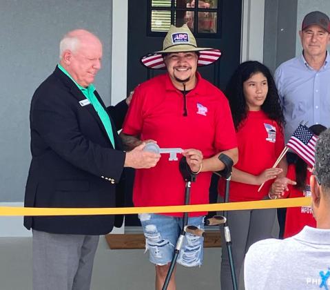 Army Sgt. Dilone receives the key to his new Kissimmee home Saturday courtesy of Homes For Our Troops. PHOTO/DAVID CHIVERS