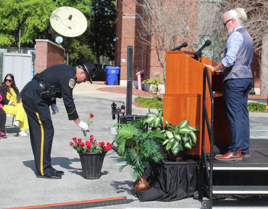A Kissimmee Police Department officer places a red rose in a vase to honor a former city employee who passed away while serving the city at Kissimmee's annual  Employee Memorial Service Friday morning. PHOTO/KEN JACKSON