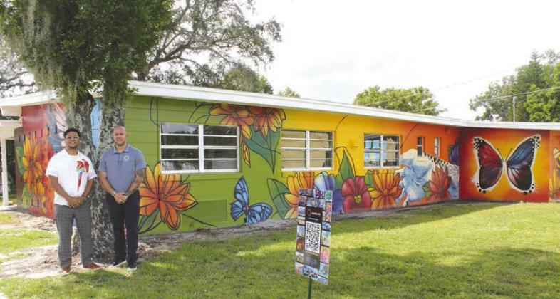 Artist Devi Sachez (left) and Osceola Arts Public Arts Coordinator Brian Camacho brought a new vivid—and immersive—ARTisNOW mural to life in Orange Gardens. It all starts with the QR code. (Photo/Photog)